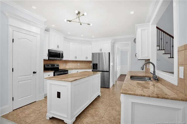 a kitchen with stainless steel appliances granite countertop a sink stove refrigerator and cabinets