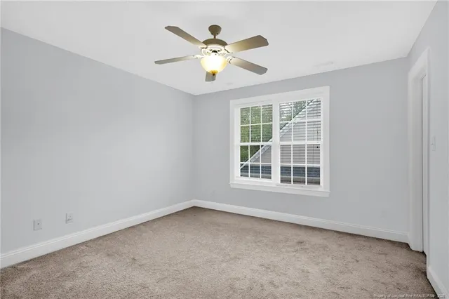 an empty room with window and ceiling fan