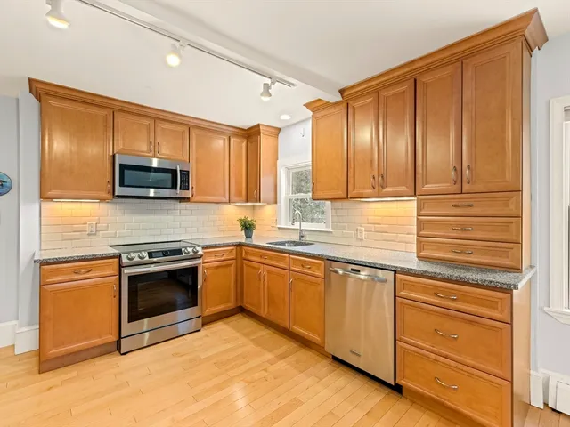 a kitchen with granite countertop wooden cabinets stainless steel appliances and a window