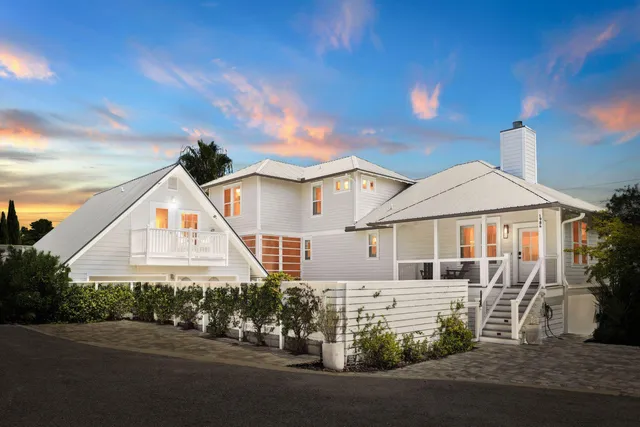 a view of a white house next to a road and a yard