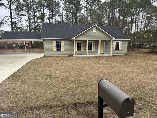 a front view of house with yard and trees in the background