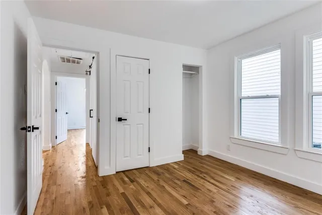 a view of empty room with wooden floor and window
