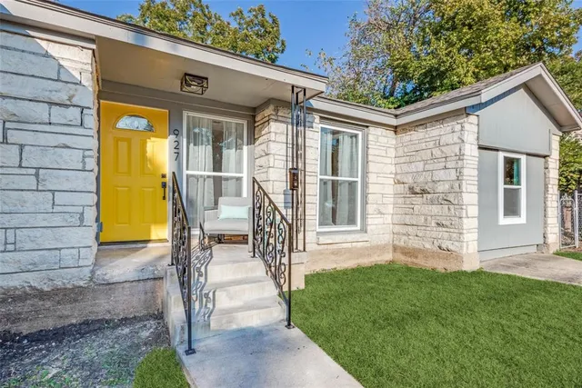 a view of a house with a small yard and a large tree with wooden fence