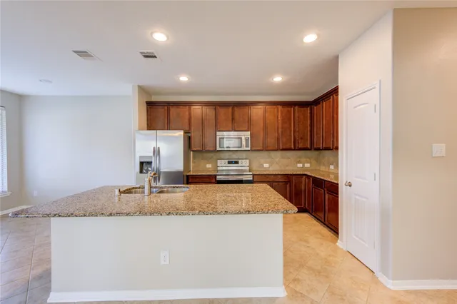 a large kitchen with granite countertop a large counter top stainless steel appliances and cabinets