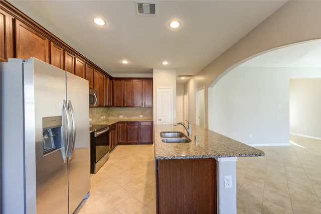 a kitchen with kitchen island granite countertop wooden cabinets a refrigerator and a sink