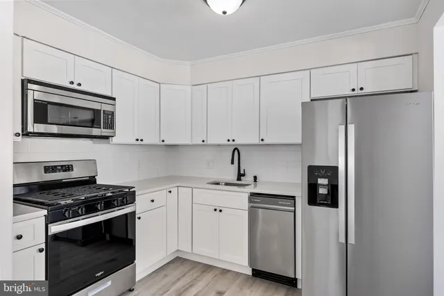 a kitchen with cabinets stainless steel appliances and wooden floor