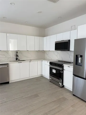 a kitchen with granite countertop a stove top oven a sink dishwasher and a refrigerator with wooden floor