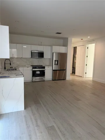 a view of kitchen with granite countertop cabinets and refrigerator