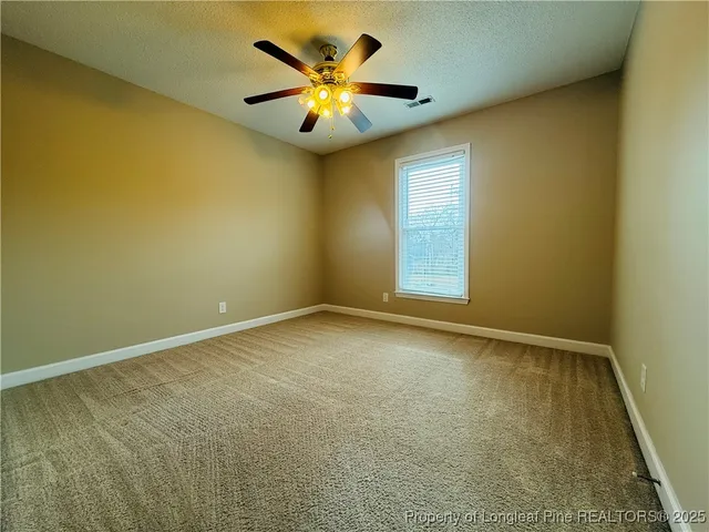 an empty room with a ceiling fan and a window