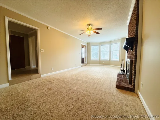 a view of an empty room with window and chandelier fan
