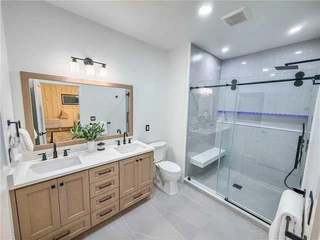 a spacious bathroom with double sink shower and a mirror