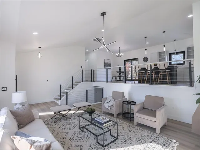 a living room with furniture kitchen view and a chandelier