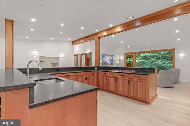 a kitchen with stainless steel appliances granite countertop a refrigerator a stove and a sink with wooden floor