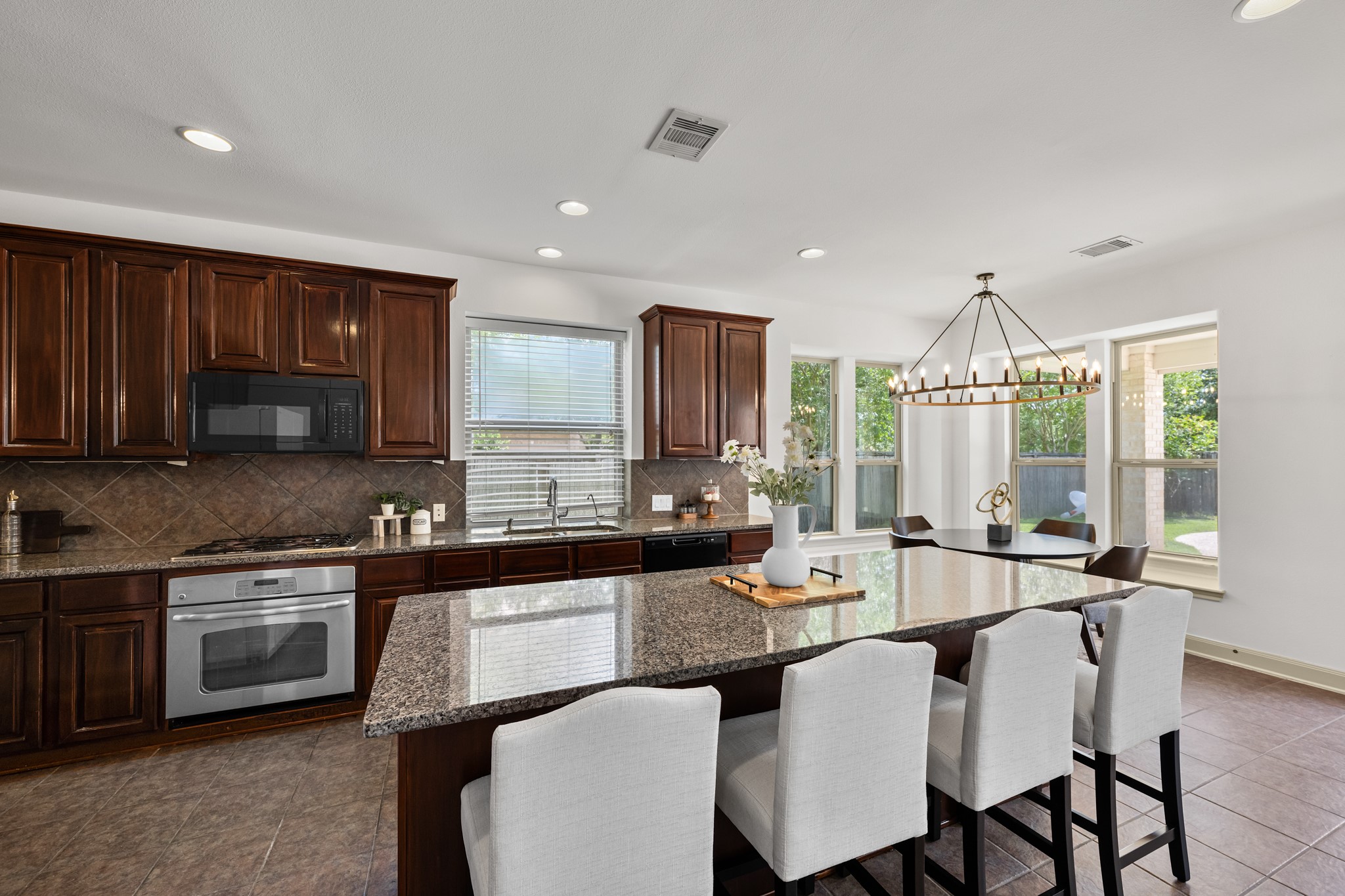 4603 Red Hawk Court Sugar Land, TX 77479 - Photo 7 of 50 a kitchen with stainless steel appliances granite countertop a stove a sink dishwasher a microwave oven and a dining table with wooden cabinet