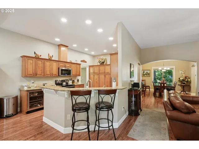 a open kitchen with stainless steel appliances kitchen island granite countertop a table chairs and a refrigerator