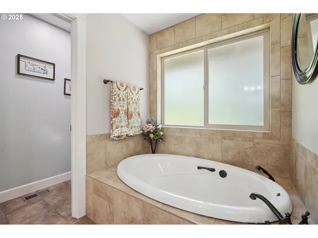 a bathroom with a tub a mirror and a shower