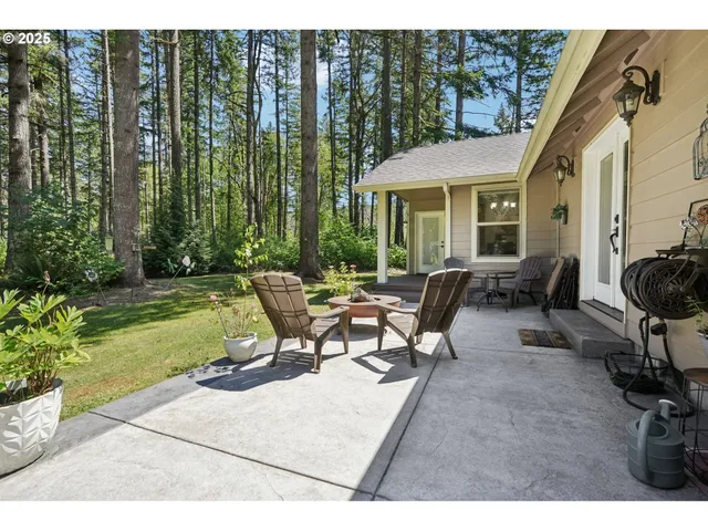 a view of a patio with table and chairs potted plants and floor to ceiling window