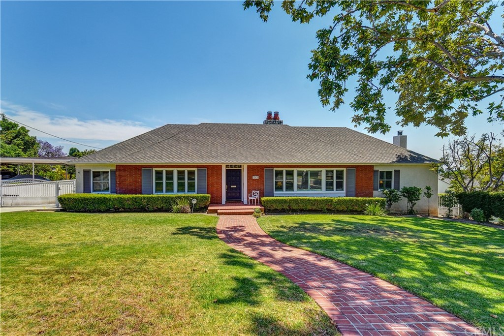 a view of a big house with a big yard potted plants and large tree