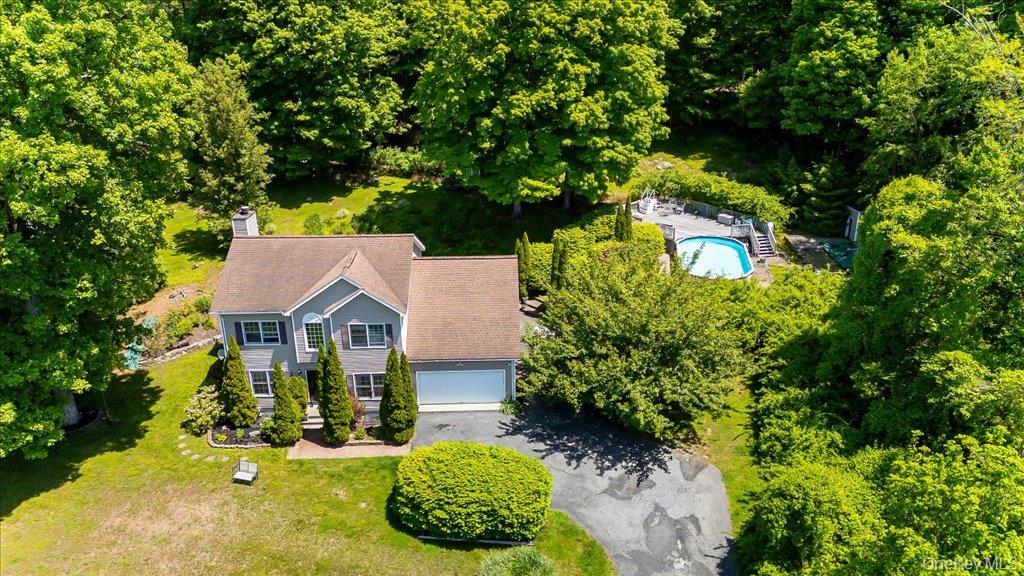 104 Wiccopee Road Putnam Valley, NY 10579 - Photo 2 of 50 Colonial-style residence featuring a prominent front gable, integrated two-car garage, and a private rear swimming pool with surrounding patio