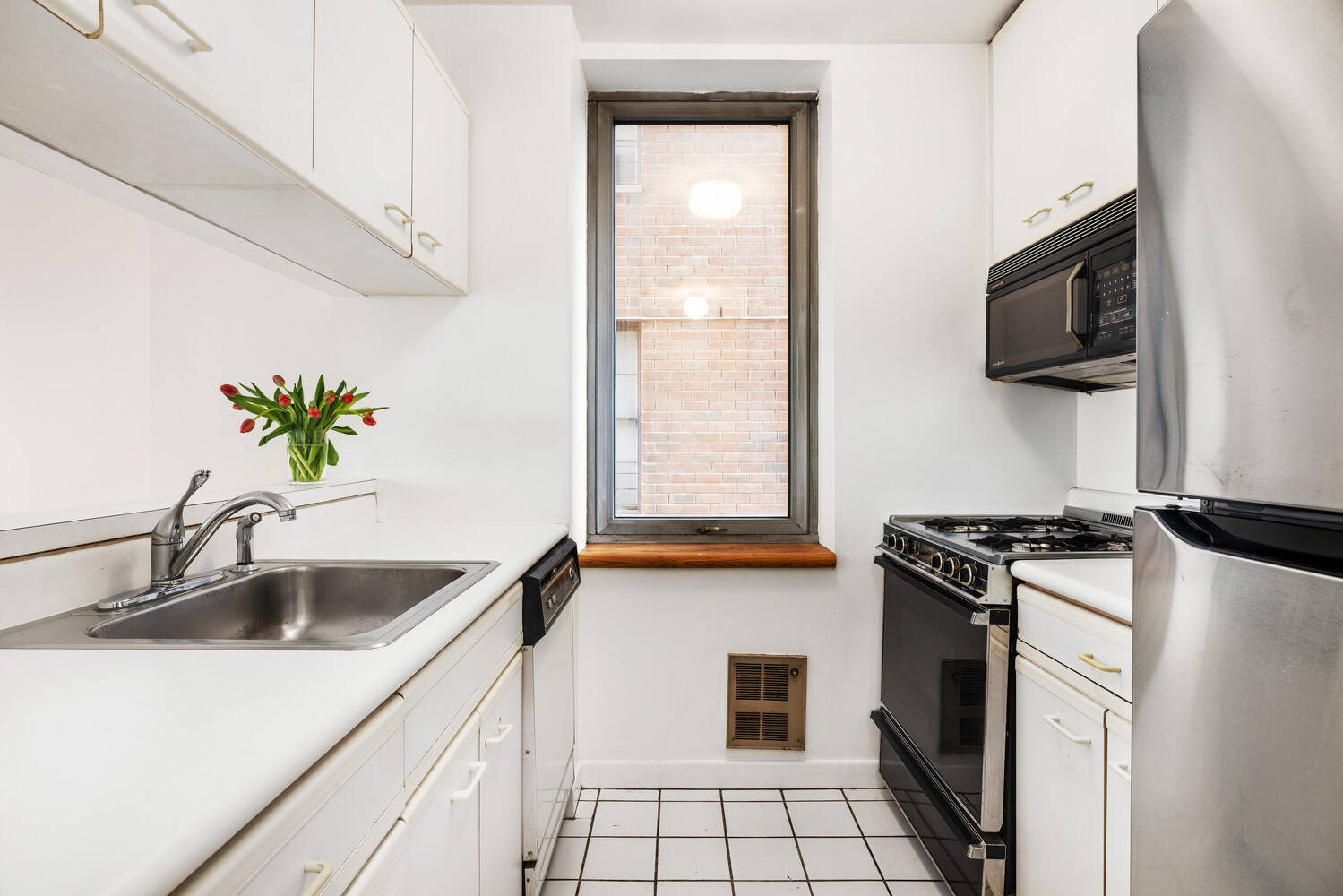 401 East 84th Street, Unit 5D Manhattan, NY 10028 - Photo 4 of 7 a kitchen with a sink a stove and microwave