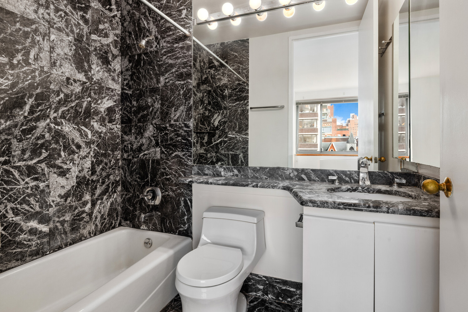 401 East 84th Street, Unit 5D Manhattan, NY 10028 - Photo 6 of 7 a bathroom with a granite countertop toilet sink and mirror
