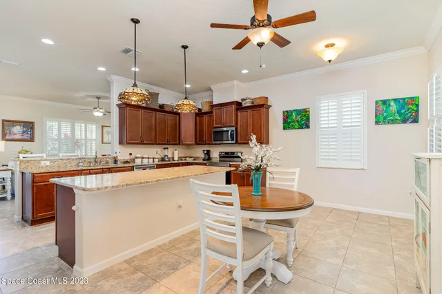 a kitchen with stainless steel appliances kitchen island granite countertop a sink a stove a dining table and chairs