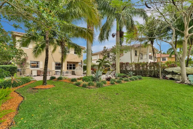 a view of a house with a big yard and palm trees