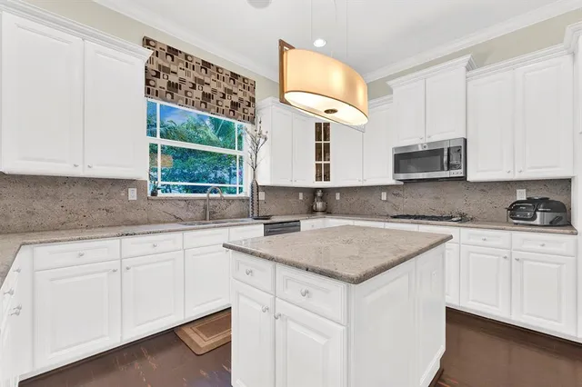 a kitchen with white cabinets appliances a sink and a window