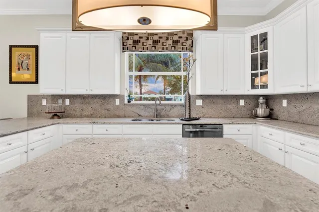 a kitchen with granite countertop a stove a sink and a white cabinets