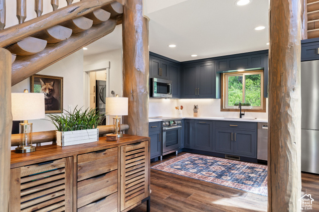 917 West Deep Forest Road Coalville, UT 84017 - Photo 7 of 41 Rustic wood log staircase, wood-finish flooring, kitchen featuring blue cabinetry, stainless steel appliances, and white countertops