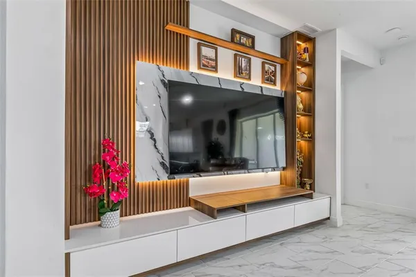 a living room with furniture and a flat screen tv with a ceiling fan