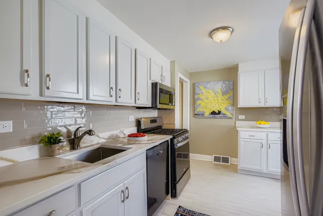 a kitchen with stainless steel appliances granite countertop a sink a stove and a refrigerator