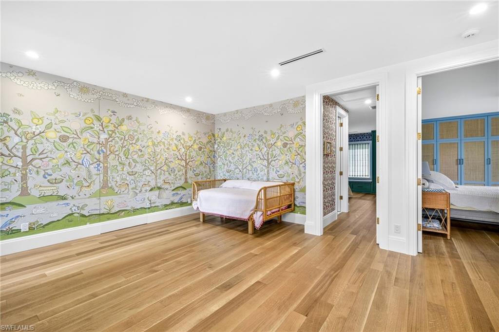 111 Caribbean Road Naples, FL 34108 - Photo 29 of 50 a spacious bedroom with a bed and wooden floor