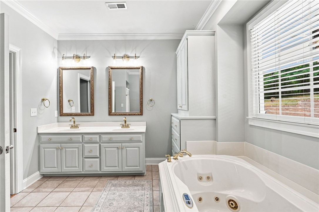 320 Watson Road Easley, SC 29642 - Photo 21 of 50 Ornate molding, tiled flooring, and a jetted tub define this primary bathroom.