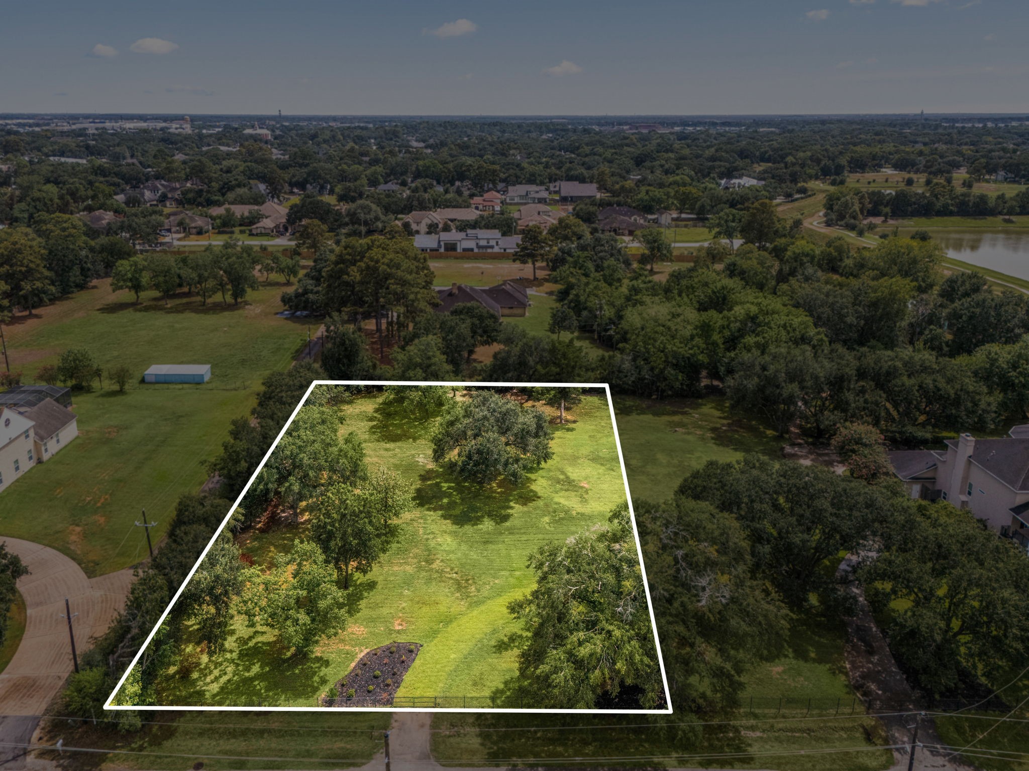 This 1.010-acre homesite is framed by mature oak trees and wrought iron fencing along the front, offering privacy on a quiet street in Old Towne Katy.