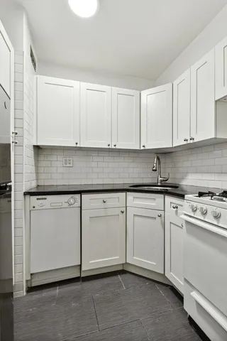 a kitchen with granite countertop white cabinets and white appliances