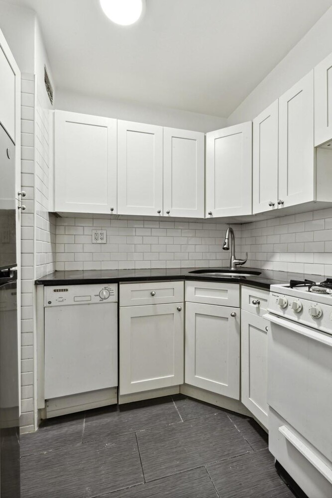333 East 46th Street, Unit 2C Manhattan, NY 10017 - Photo 4 of 5 a kitchen with granite countertop white cabinets and white appliances