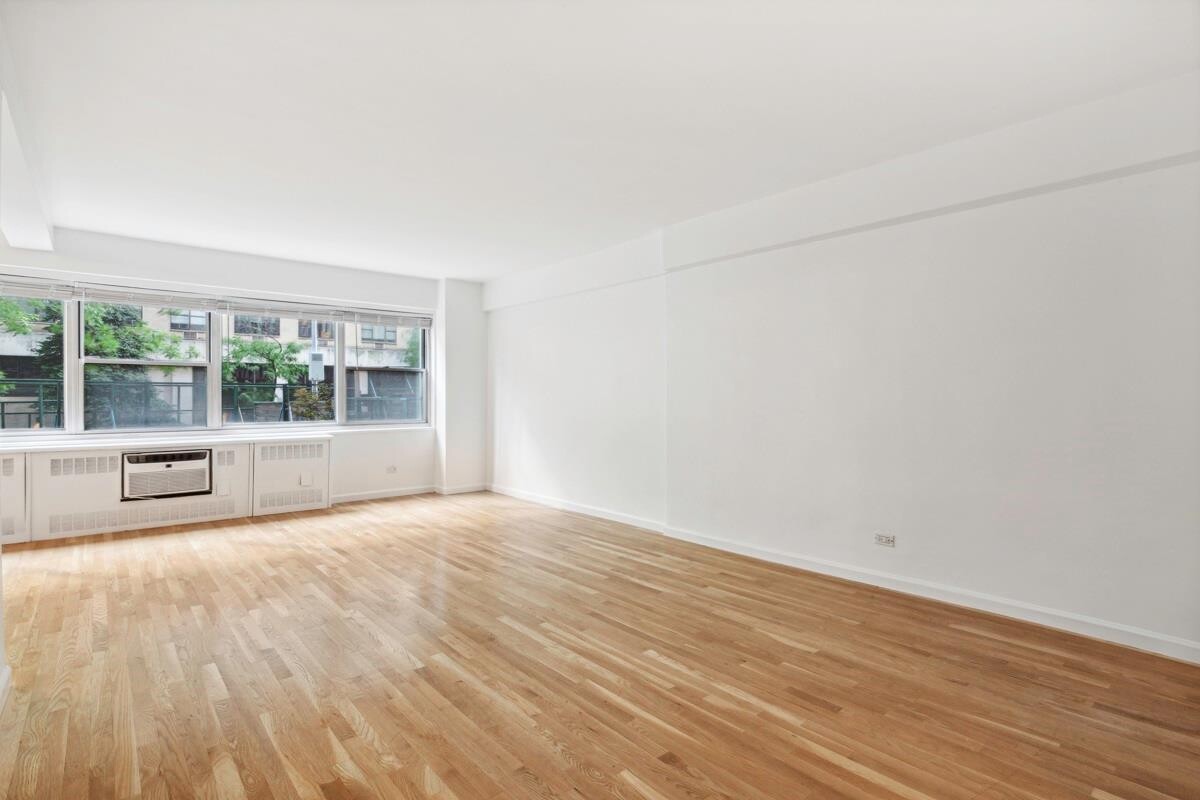 333 East 46th Street, Unit 2C Manhattan, NY 10017 - Photo 5 of 5 a view of an empty room with wooden floor and a window