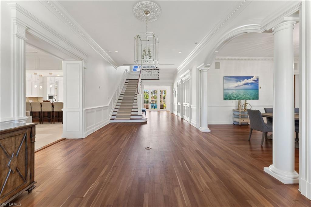 2325 Lantern Lane Naples, FL 34102 - Photo 12 of 50 Entryway with a decorative wall, ornate columns, ornamental molding, wood finished floors, and stairs