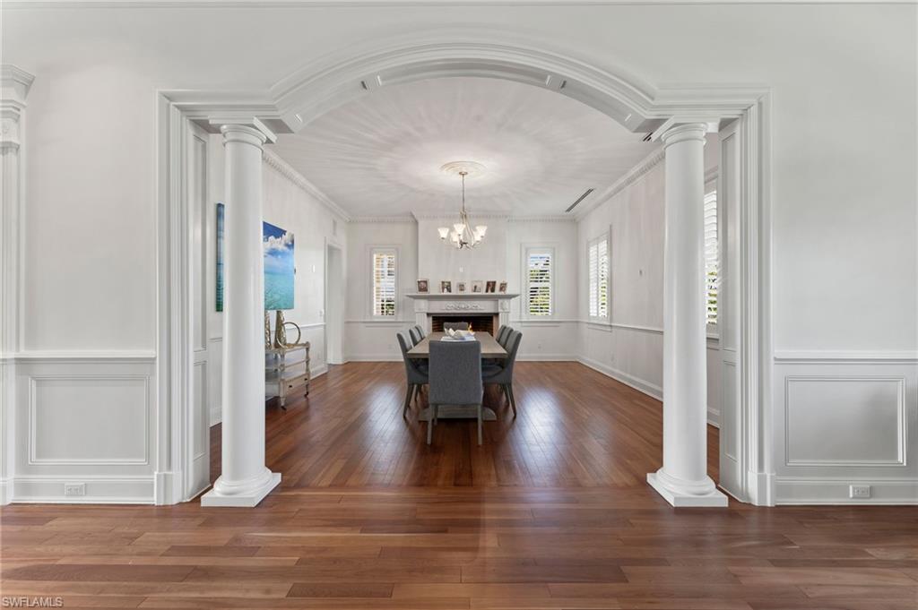 2325 Lantern Lane Naples, FL 34102 - Photo 14 of 50 Dining room with an inviting chandelier, ornamental molding, decorative columns, a decorative wall, and wood finished floors