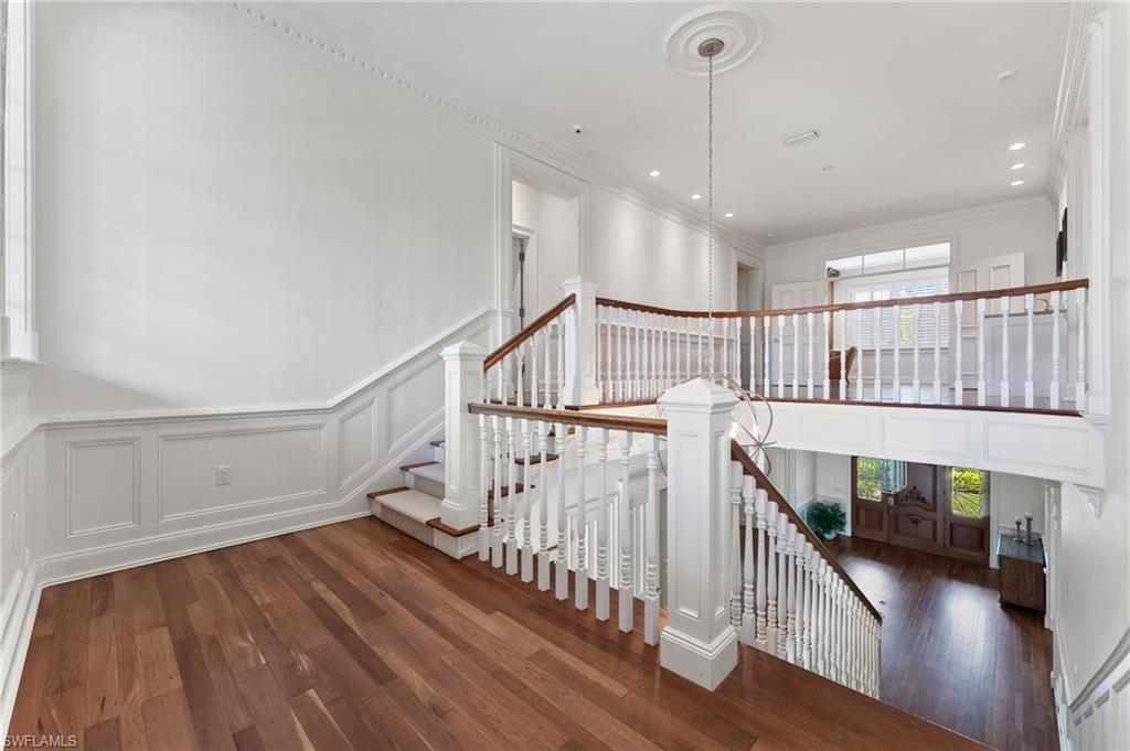 2325 Lantern Lane Naples, FL 34102 - Photo 25 of 50 Stairs featuring a healthy amount of sunlight, wood finished floors, and a decorative wall