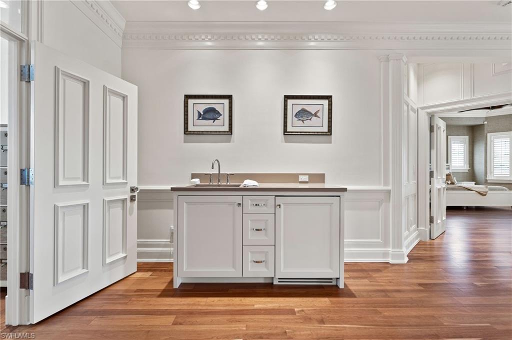 2325 Lantern Lane Naples, FL 34102 - Photo 27 of 50 Bar featuring light wood-style floors, a decorative wall, wet bar, ornamental molding, and a sink
