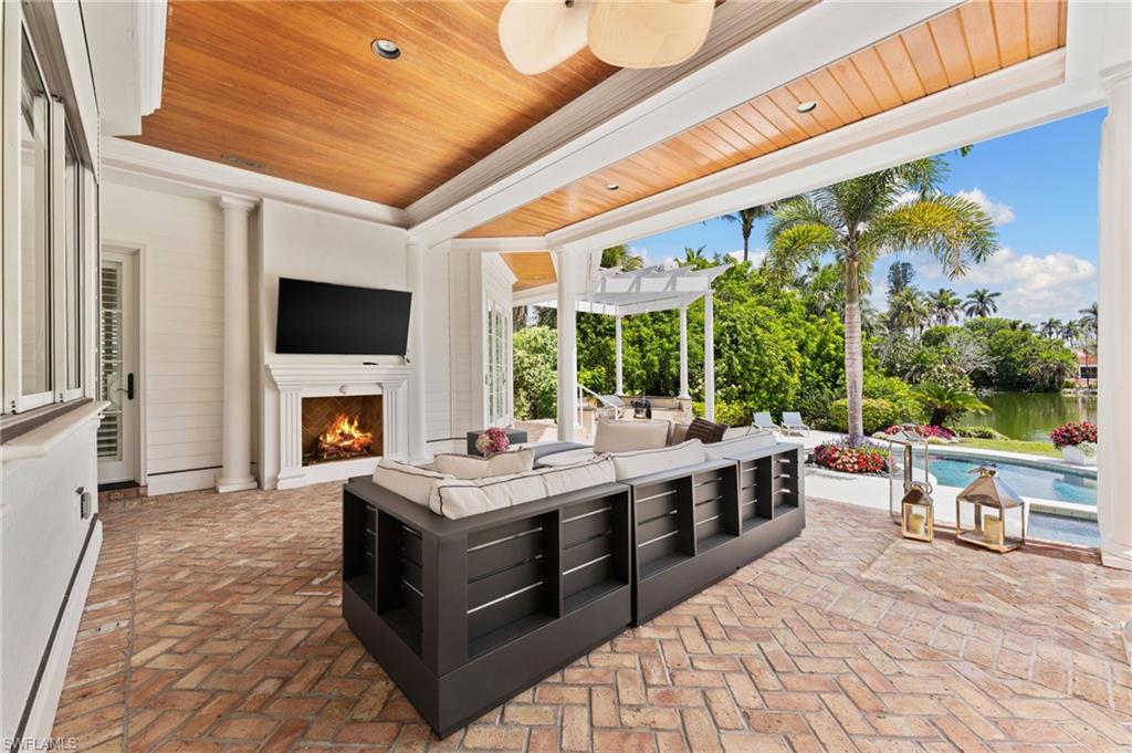 2325 Lantern Lane Naples, FL 34102 - Photo 40 of 50 View of patio / terrace featuring a pergola, an outdoor living space with a fireplace, a ceiling fan, a baseboard radiator, and a fenced in pool