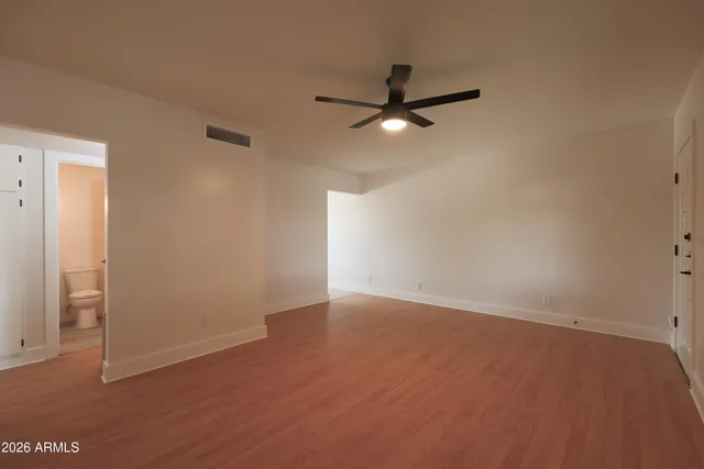 an empty room with closet and a ceiling fan