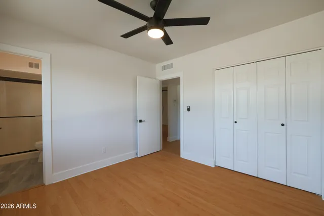 a view of empty room with wooden floor and fan