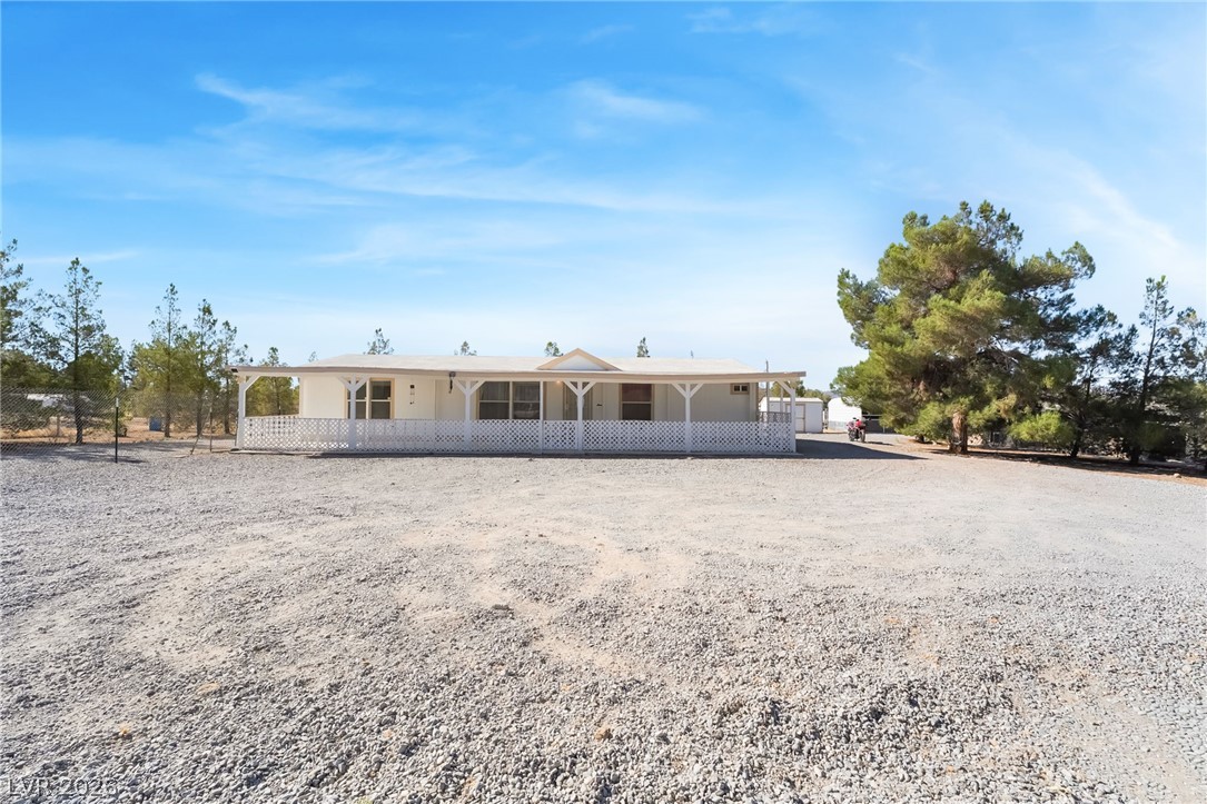 1551 West Wilson Road Pahrump, NV 89048 - Photo 2 of 68 A spacious gravel driveway leads toward the expansive covered porch of this one-story residence.