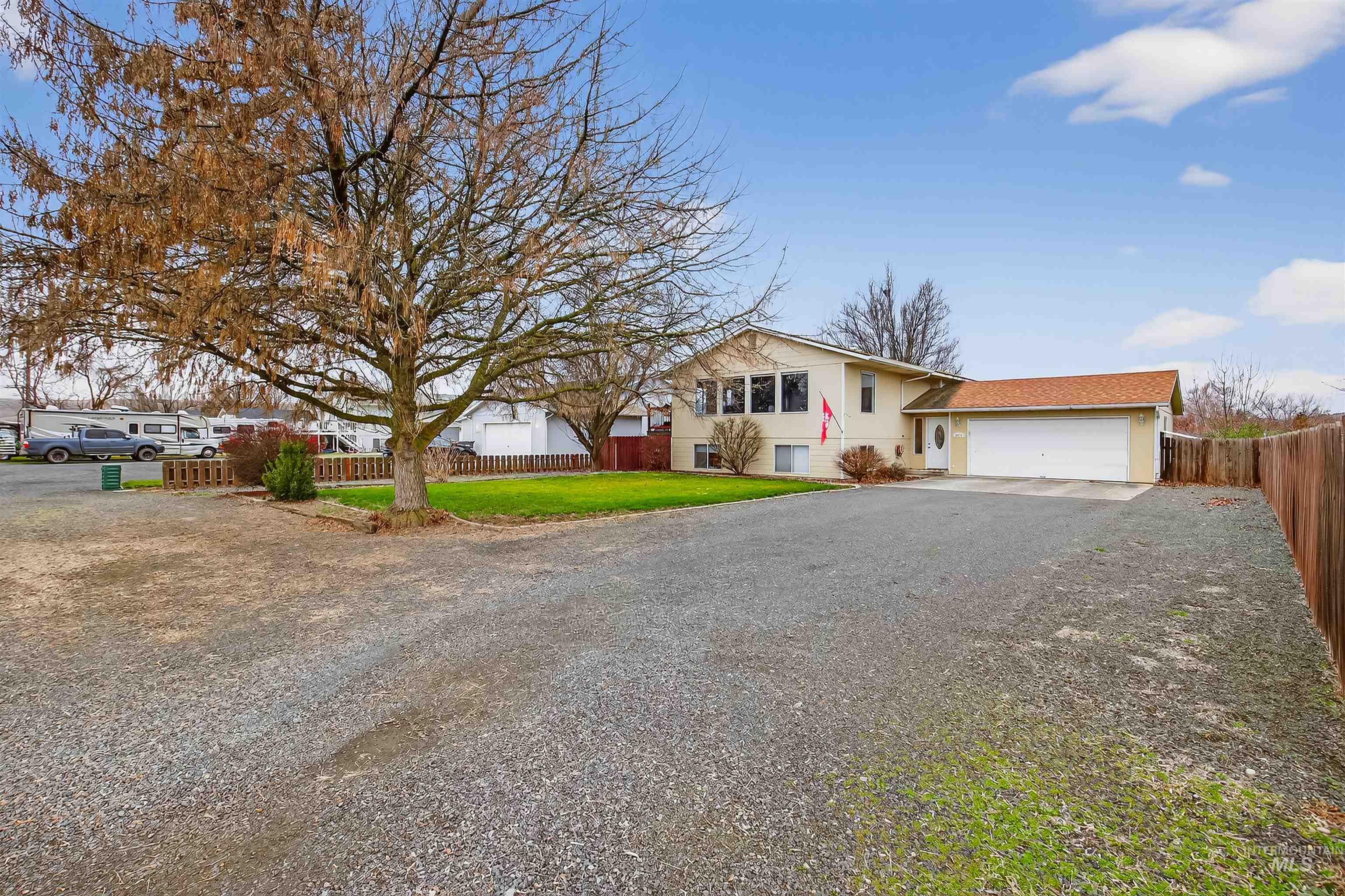 View of front of property with gravel driveway, an attached garage, and a residential view