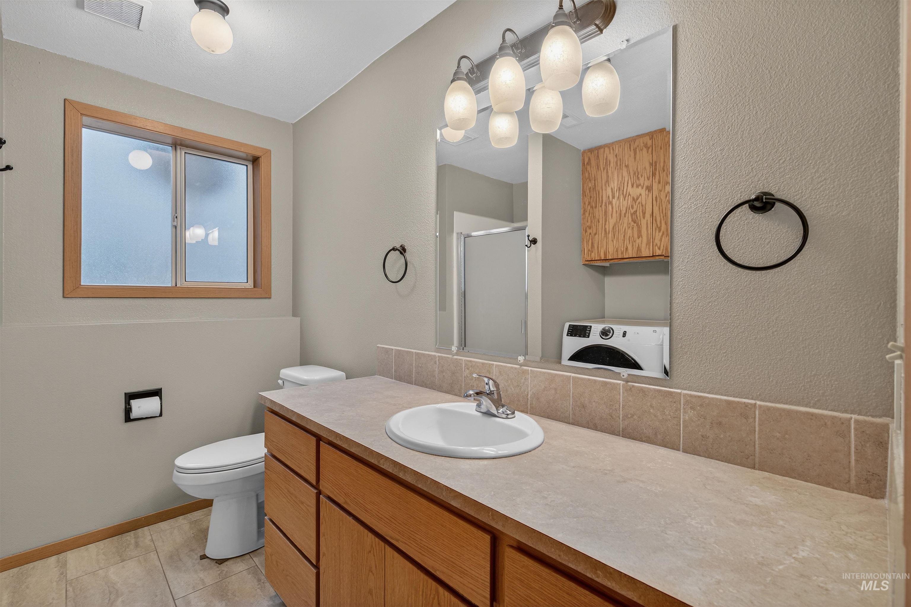 2814 22nd Street Clarkston, WA 99403 - Photo 25 of 33 Bathroom featuring a shower stall, vanity, washer / dryer, and a textured wall