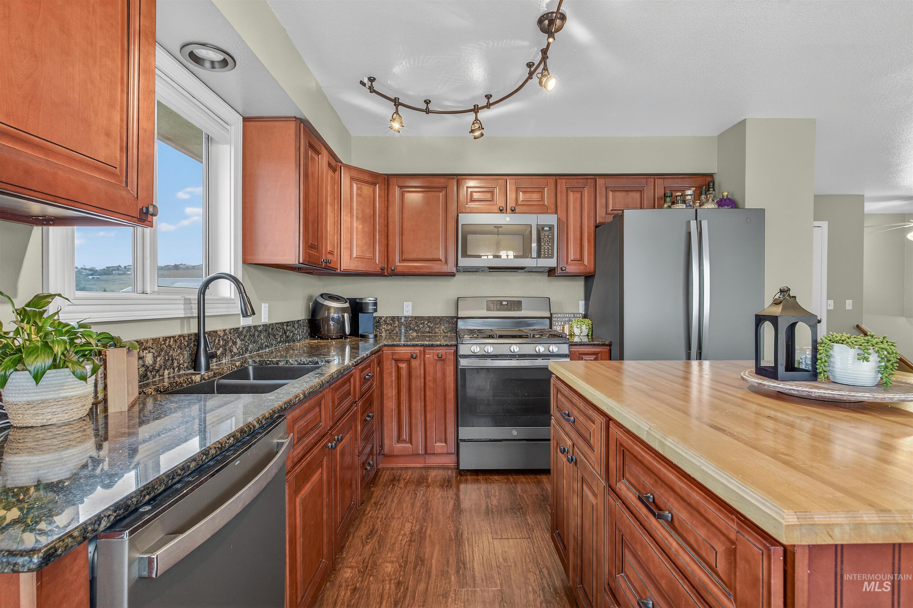 2814 22nd Street Clarkston, WA 99403 - Photo 4 of 33 Kitchen with stainless steel appliances, dark wood-style flooring, brown cabinetry, a kitchen island, and wood counters