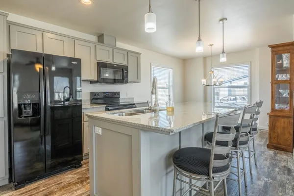 a kitchen with stainless steel appliances granite countertop a stove refrigerator a sink dishwasher a dining table and chairs with wooden floor